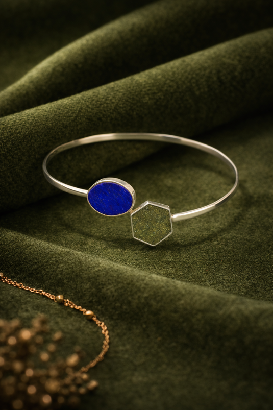 Silver bracelet with a blue gemstone on a green fabric background